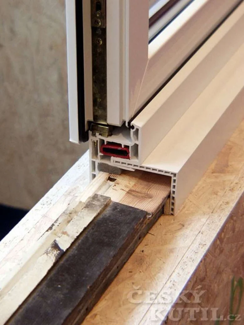 Detailní pohled na spodní rámeček okna s viditelnými mezerami způsobujícími průvan.