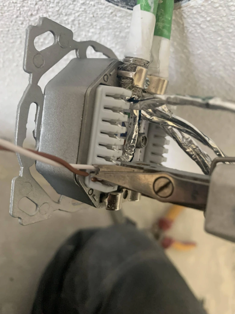 Připojení fázového kabelu do zásuvky pomocí kleští na elektrickém rozvaděči.