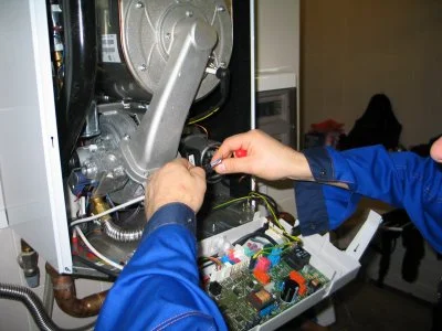Ruční oprava ventilu plynového kotle s použitím nástrojů.