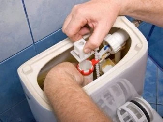 Ruce opravují vnitřní mechanismy bílé toaletní nádrže.