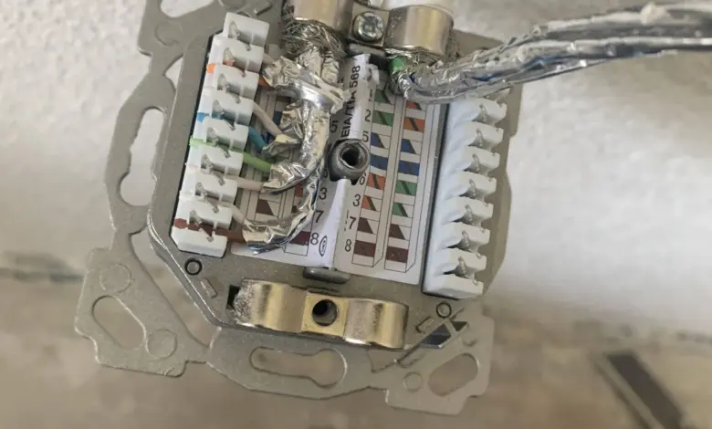 Otevřená elektrická zásuvka s viditelnými vodiči a nástroji pro kontrolu připojení.