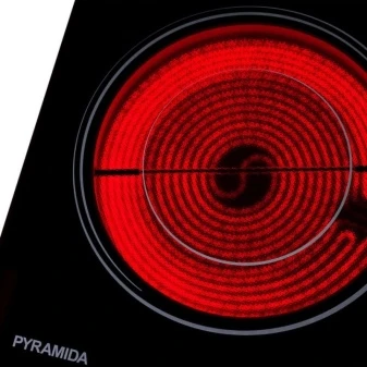 Zapálený spirální topný prvek elektrického sporáku značky Pyramida.