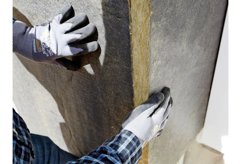 Ruční instalace izolačního materiálu do stavebního systému.