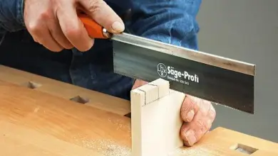 Ruční pila řezá dřevěný spoj na stolní pilovém stole.
