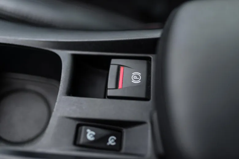 Tlačítko elektronické parkovací brzdy v interiéru automobilu.
