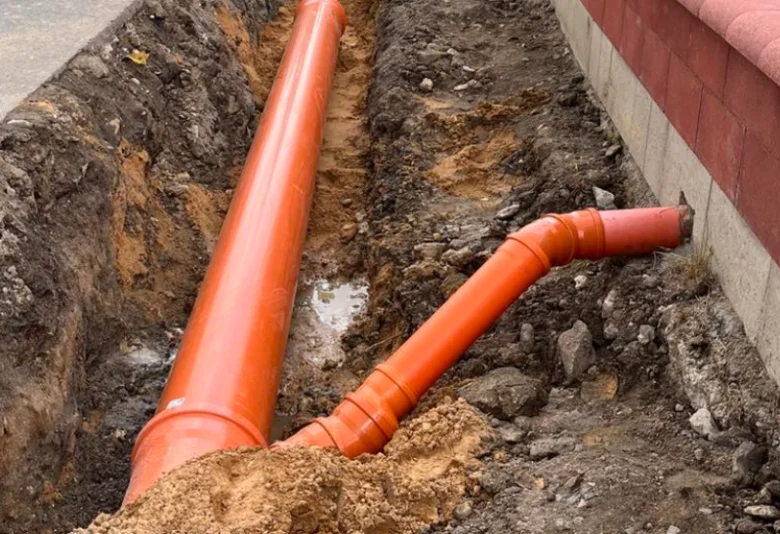 Oranžová kanalizační trubice v příkopu pro připojení WC.