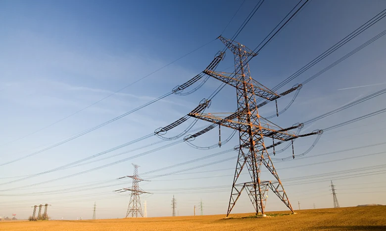 Vysokonapěťové elektrické vedení s věžemi na otevřeném poli.