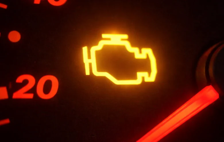 Rozsvícená kontrolka motoru na přístrojové desce automobilu.