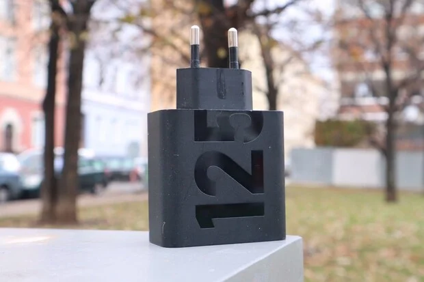 Černý napájecí adaptér pro notebook s výřezem čísla 125.