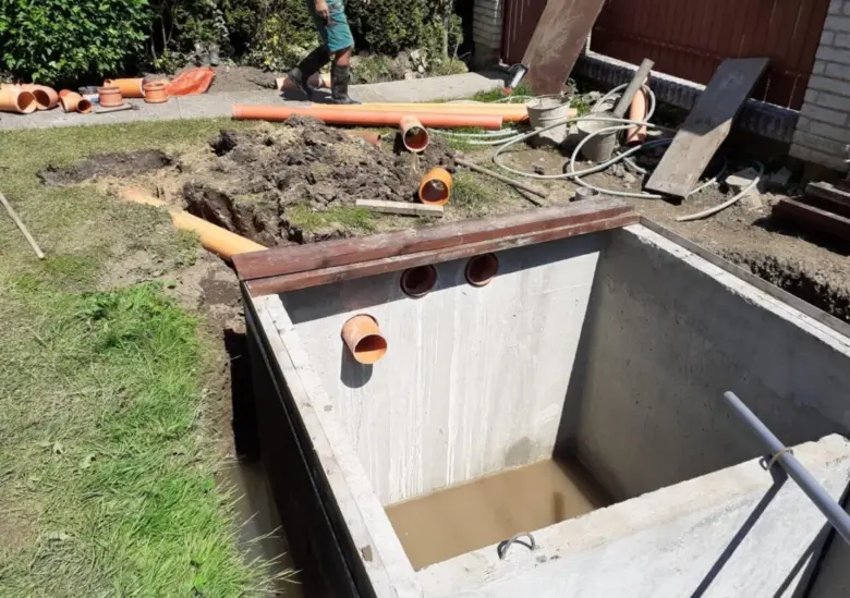 Instalace betonového septiku s připojenými kanalizačními trubkami.
