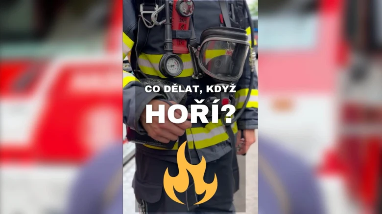 Hasič v plné výbavě před hasicím vozidlem.