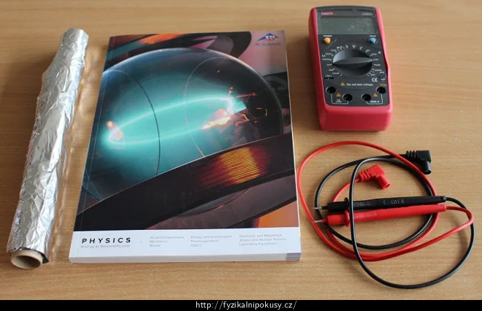 Fyzikální učebnice s měřicím přístrojem pro experimenty.