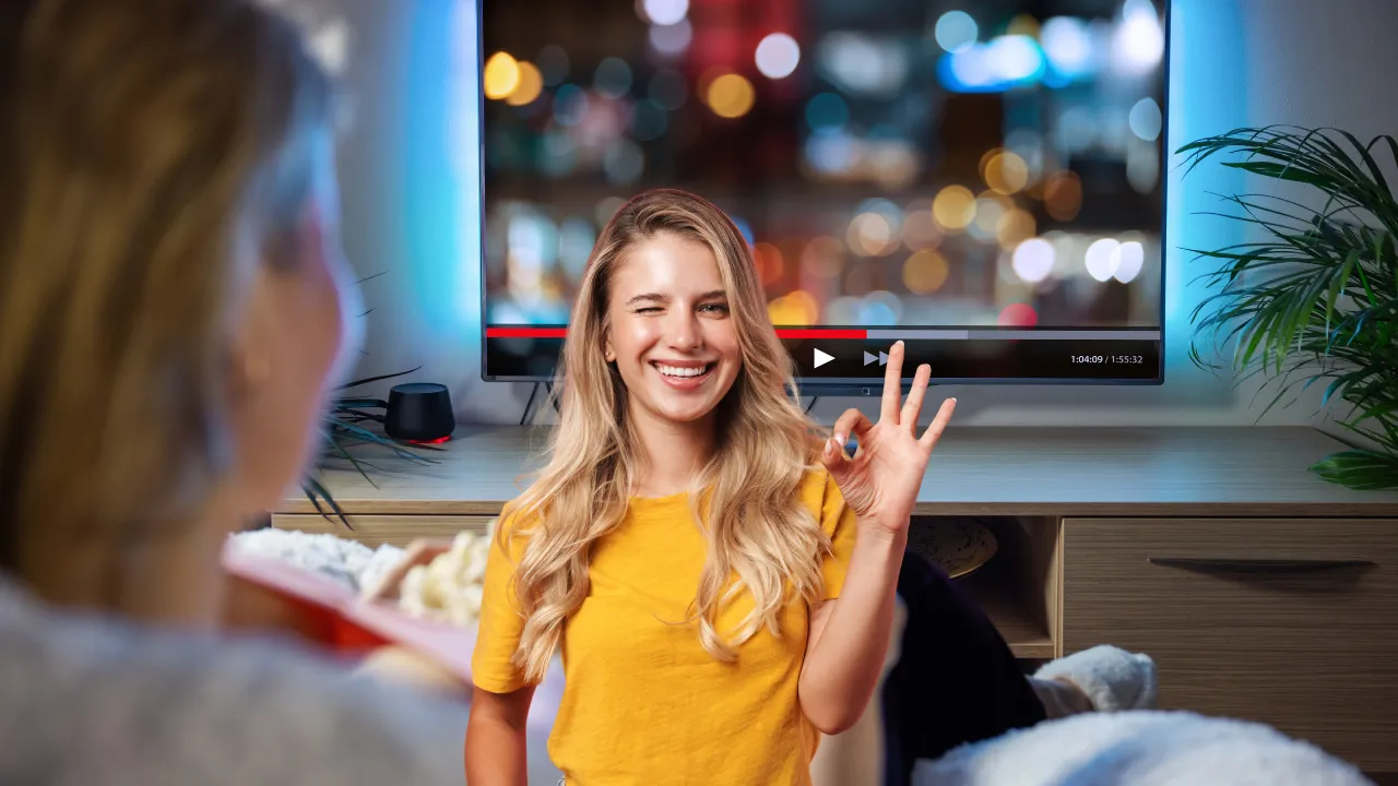Dívka se dívá na televizi s kamarátkou v obývacím pokoji.