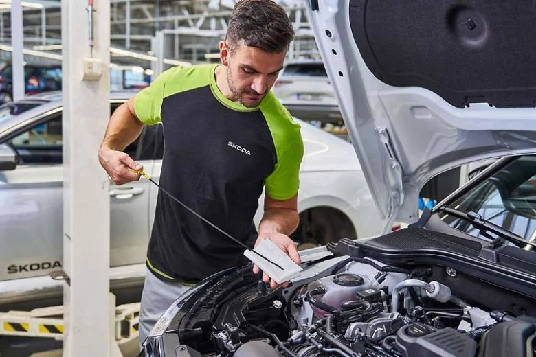 Mechanik kontroluje hladinu motorového oleje pod kapotou vozu.