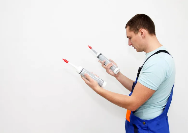 Instalatér drží dvě tuby tmelu pro vodoinstalaci.