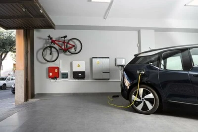 Elektromobil nabíjený na stěnné stanici v garáži s bezpečnostními boxy.