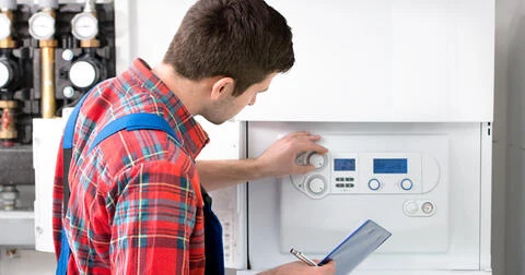 Technik upravuje ovládací panel kondenzačního kotle při údržbě.