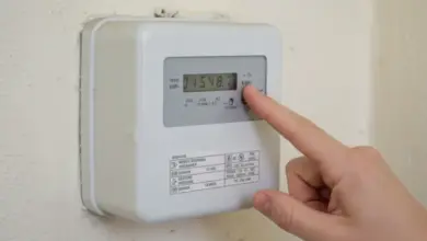 Ruka stiská tlačítko na elektroměru pro zobrazení čtení.