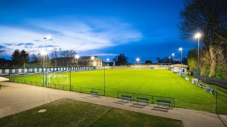 Osvětlené fotbalové hřiště pod stadionovými reflektory v západu slunce.