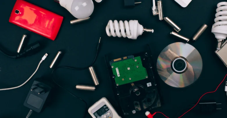 Různé druhy elektronického odpadu včetně zářivek na tmavém pozadí.