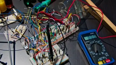 Elektronická sestava s plošnou deskou, diodami a multimetrem na pracovním stole.