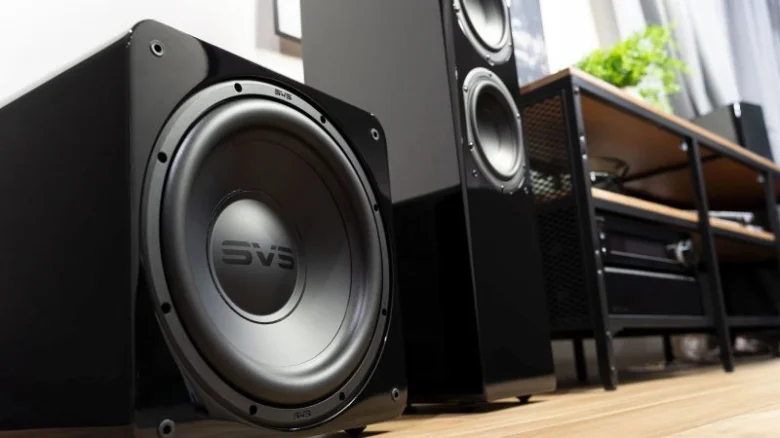 Černý subwoofer značky SVS vedle vysokých reproduktorů v obýváku.