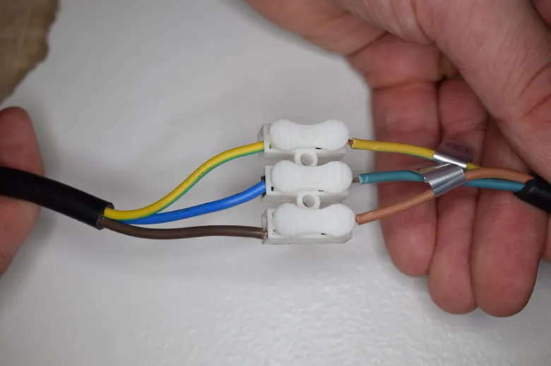 Bílé spojky pro elektrické vodiče při instalaci LED žárovky.
