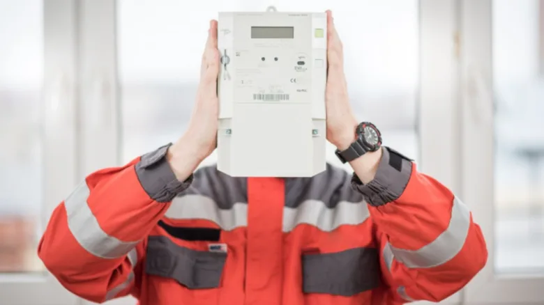 Montér drží nový elektroměr před obličejem při výměně.