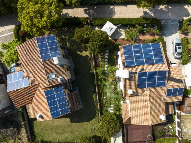 Vzdušný pohled na domy s fotovoltaickými panely na střechách.