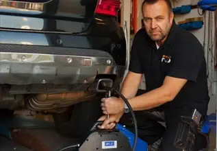 Mechanik kontroluje výfukový systém automobilu v garáži