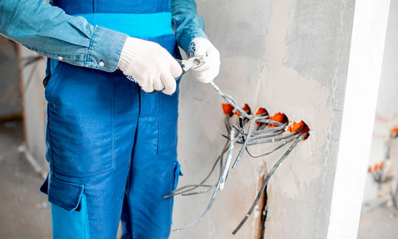 Elektrikář pracuje na instalaci drátů v zdi pro zásuvku.