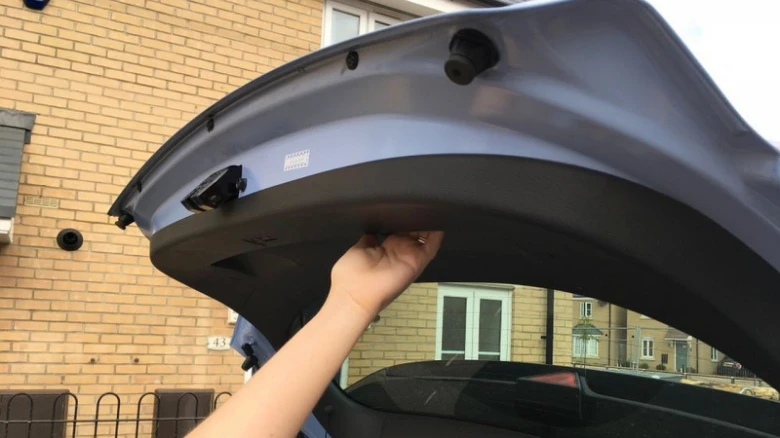 Ruka ručně zatlačí elektrický kufr auta dolů pro jeho zavření.