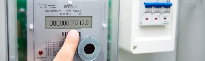 Ruka tlačí na elektroměr s displejem ukazávajícím spotřebu energie.