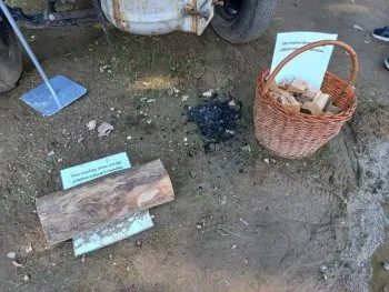 Dřevěné polena s popisky vedle košíku na venkovním pozemku.