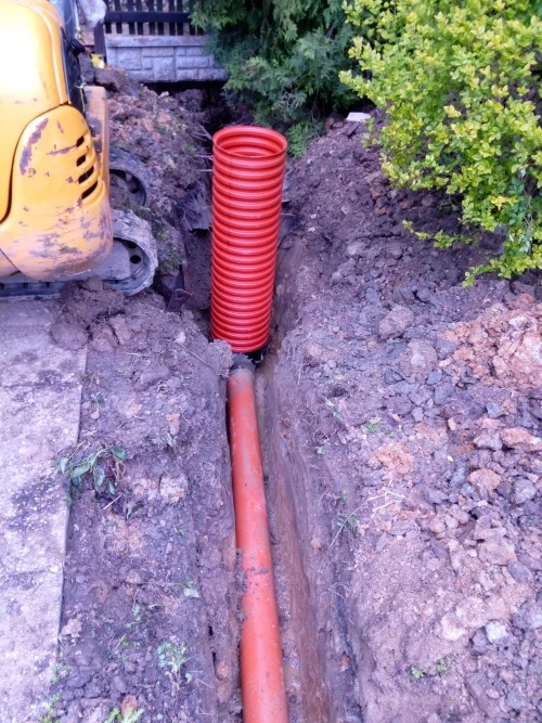 červená kanalizační trubice v zemi při instalaci