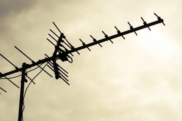 Silueta televizní antény na sloupě proti obloze.