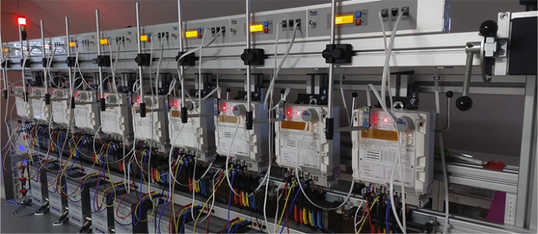 Řada elektroměrů na testovacím stojanu pro ověření bez demontáže.