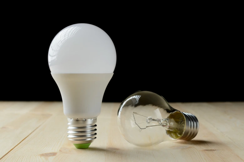 Porovnání nového LED žárovky s klasickou žárovkou na dřevěném povrchu.