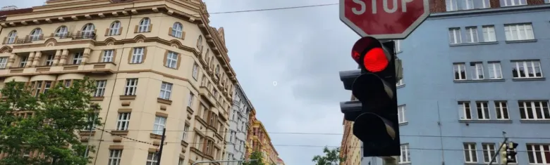 Semafor s červenou světlem na křižovatce v městském prostředí.