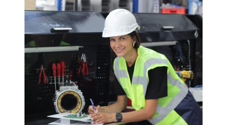 Žena v ochranném oděvu pracuje s elektrickým komponentem.