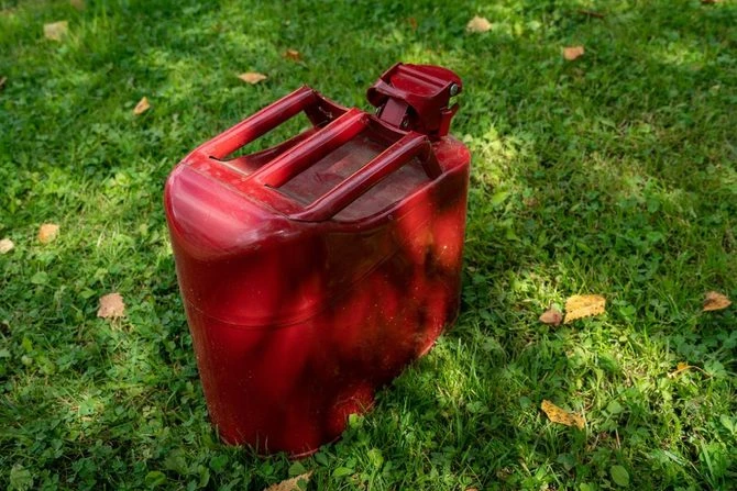 Red plastic fuel canister on grass