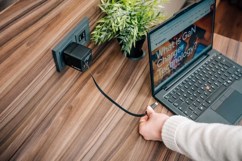Ruka zapojuje nabíječku do notebooku přes USB kabel.