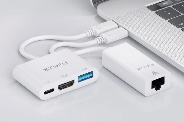 Bílý adaptér s porty USB-C pro připojení k notebooku.