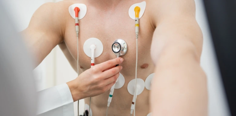 Lékař aplikuje elektrody na hrudník pacienta pro měření.