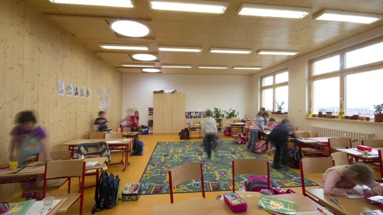Školní třída s přirozeným světlem z oken a umělým osvětlením stropními lampami.