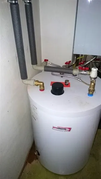 Bílý zásobník teplé vody s přípojkami pro vypnutí vodovodu.