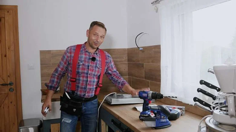 Muž s vrtákem na kuchyňské desce při instalaci.