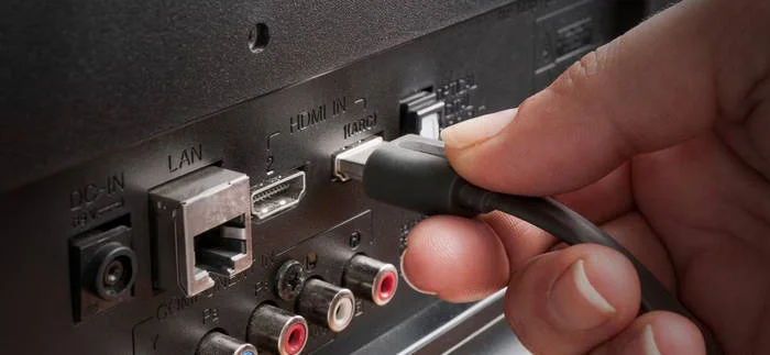Ruka zapojuje kabel HDMI do televizoru pro řešení problémů s obrazem.