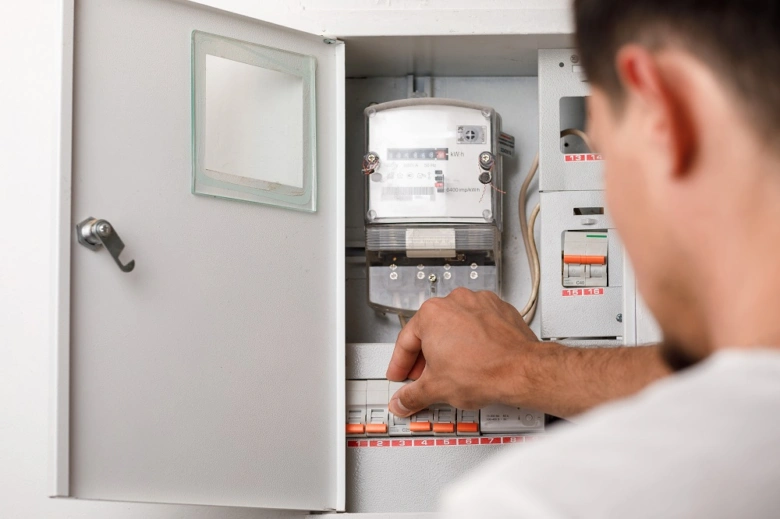 Elektrikář nastavuje jističe v rozvaděči před elektroměrem.