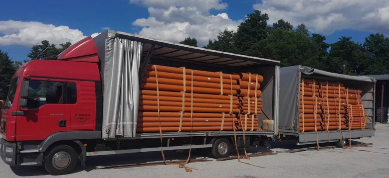 Náklad oranžových kanalizačních trubek na nákladním voze.